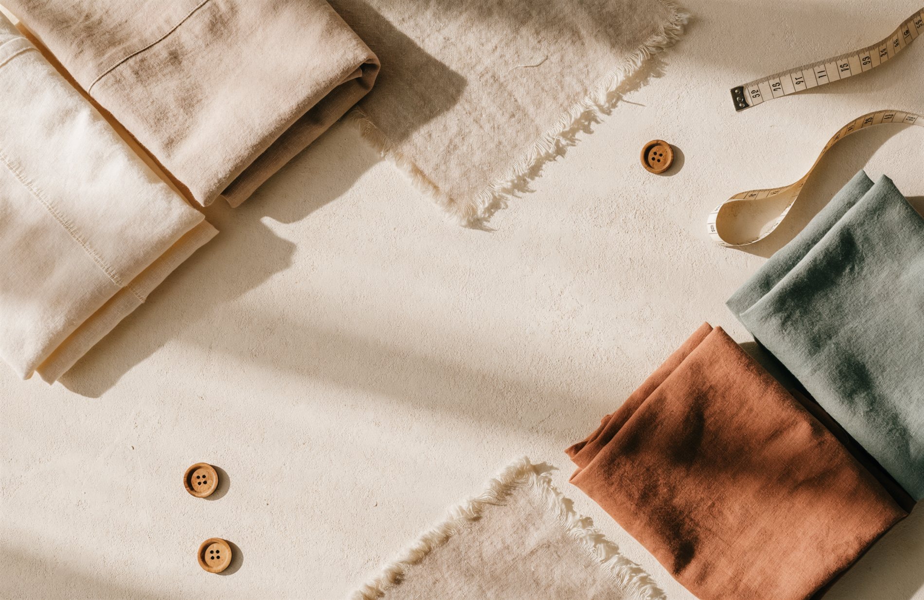 Folded Altura cotton garments with fabric swatches and a measuring tape